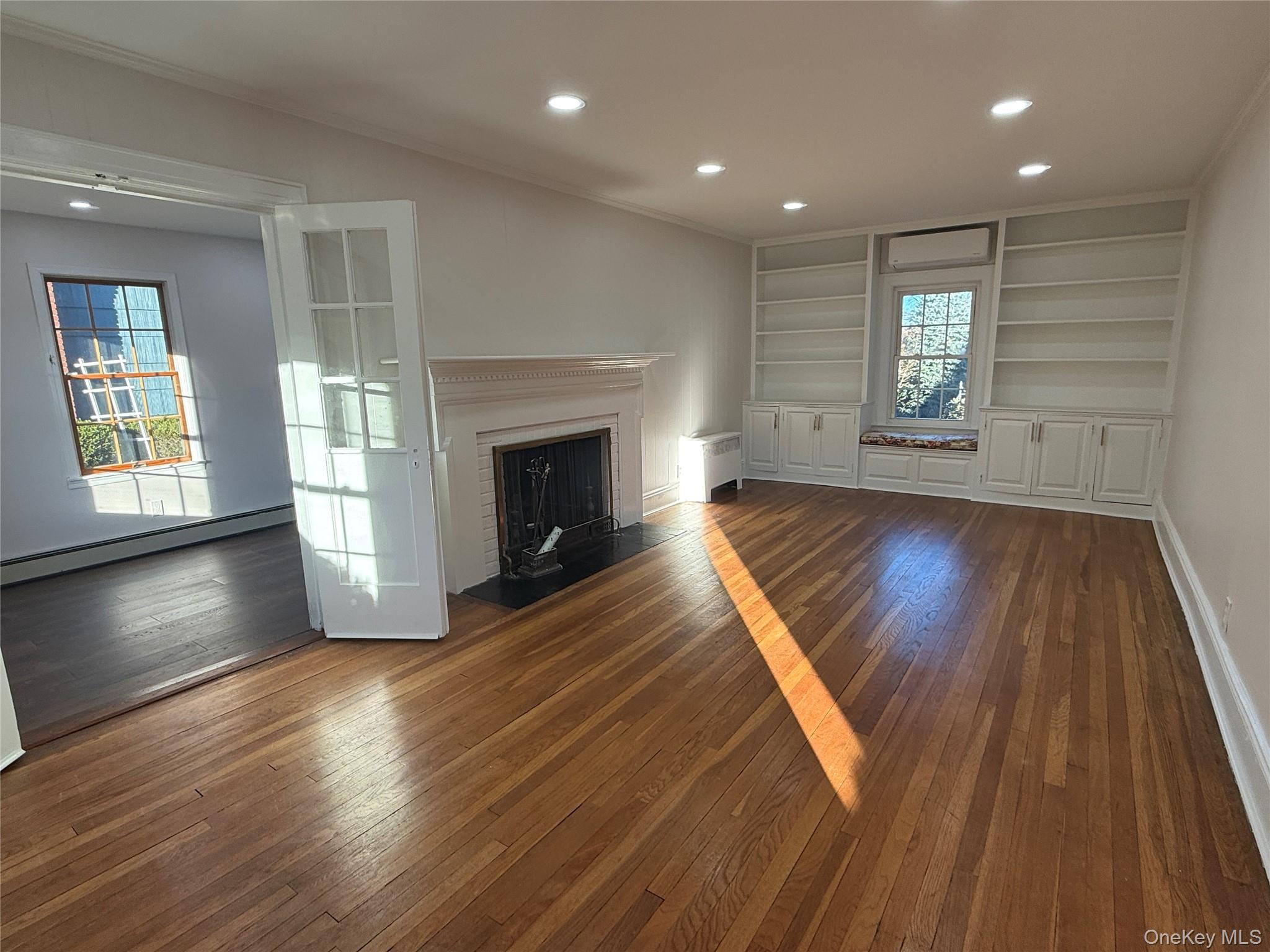71 Hillcrest Avenue Manhasset, NY 11030 - Photo 5 of 23 an empty room with wooden floor fireplace and windows