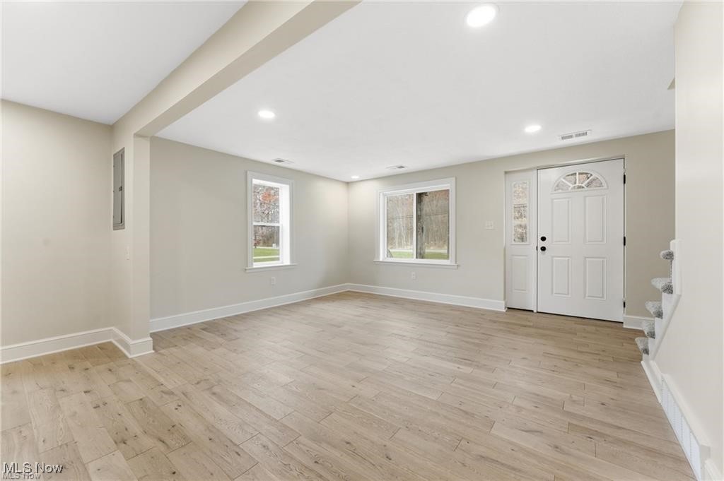 Living room entrance with light wood finished floors and recessed lighting