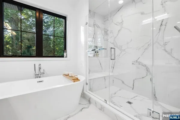 a white bath tub sitting next to a white sink and a shower