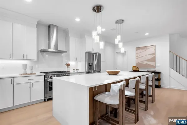a kitchen with stainless steel appliances kitchen island a table chairs sink and cabinets