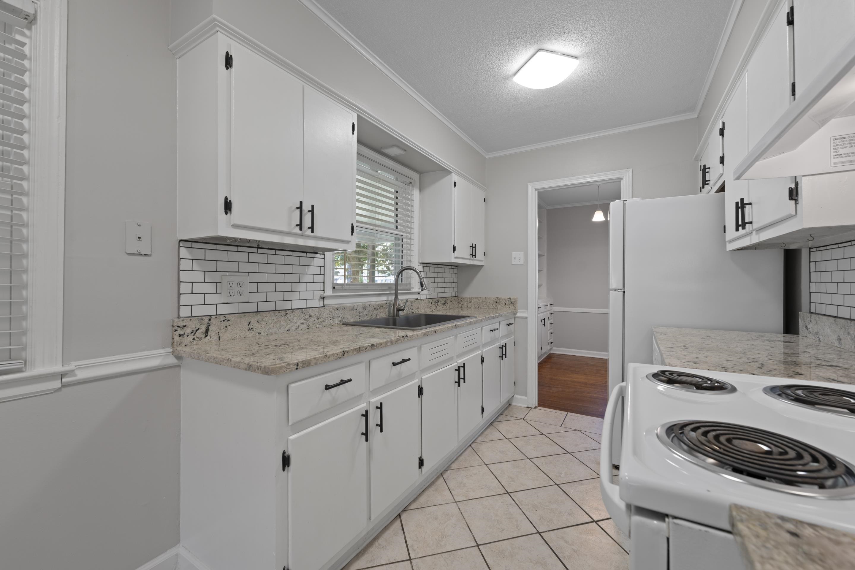 1603 Colonial Road Memphis, TN 38117 - Photo 16 of 24 a kitchen with granite countertop a sink stove and cabinets