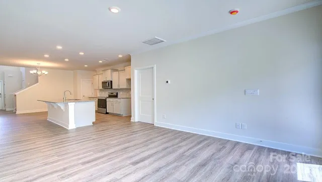 a view of kitchen with kitchen island wooden floors and stainless steel appliances