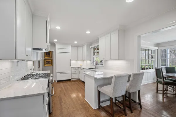 a kitchen with stainless steel appliances kitchen island granite countertop a dining table chairs and white cabinets