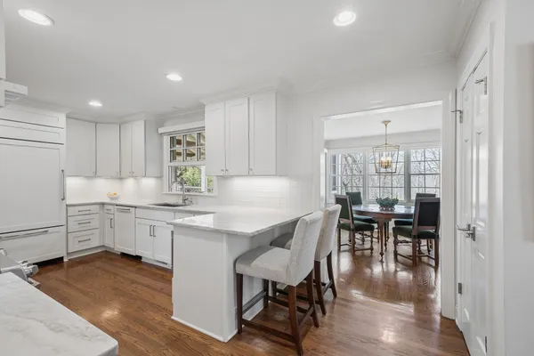 a kitchen with stainless steel appliances kitchen island granite countertop a table chairs sink and cabinets