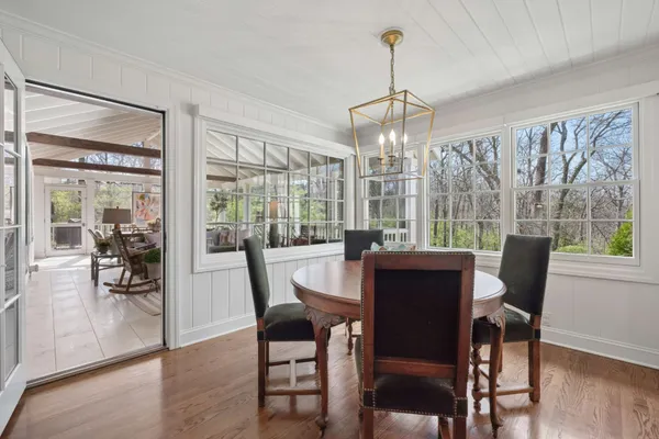 a dining room with wooden floor a chandelier a glass table and chairs