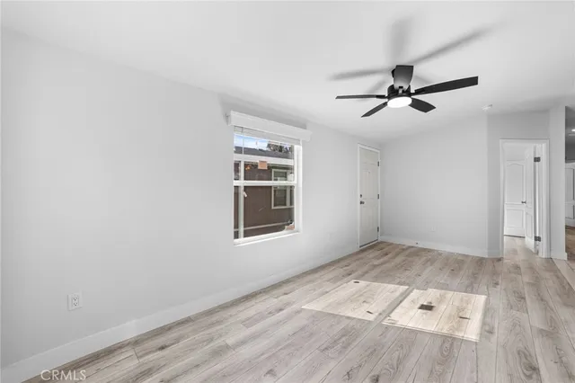 a view of empty room with wooden floor and fan