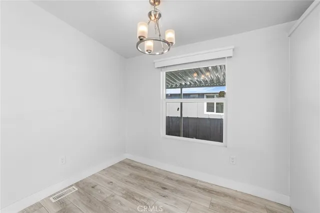 an empty room with wooden floor chandelier