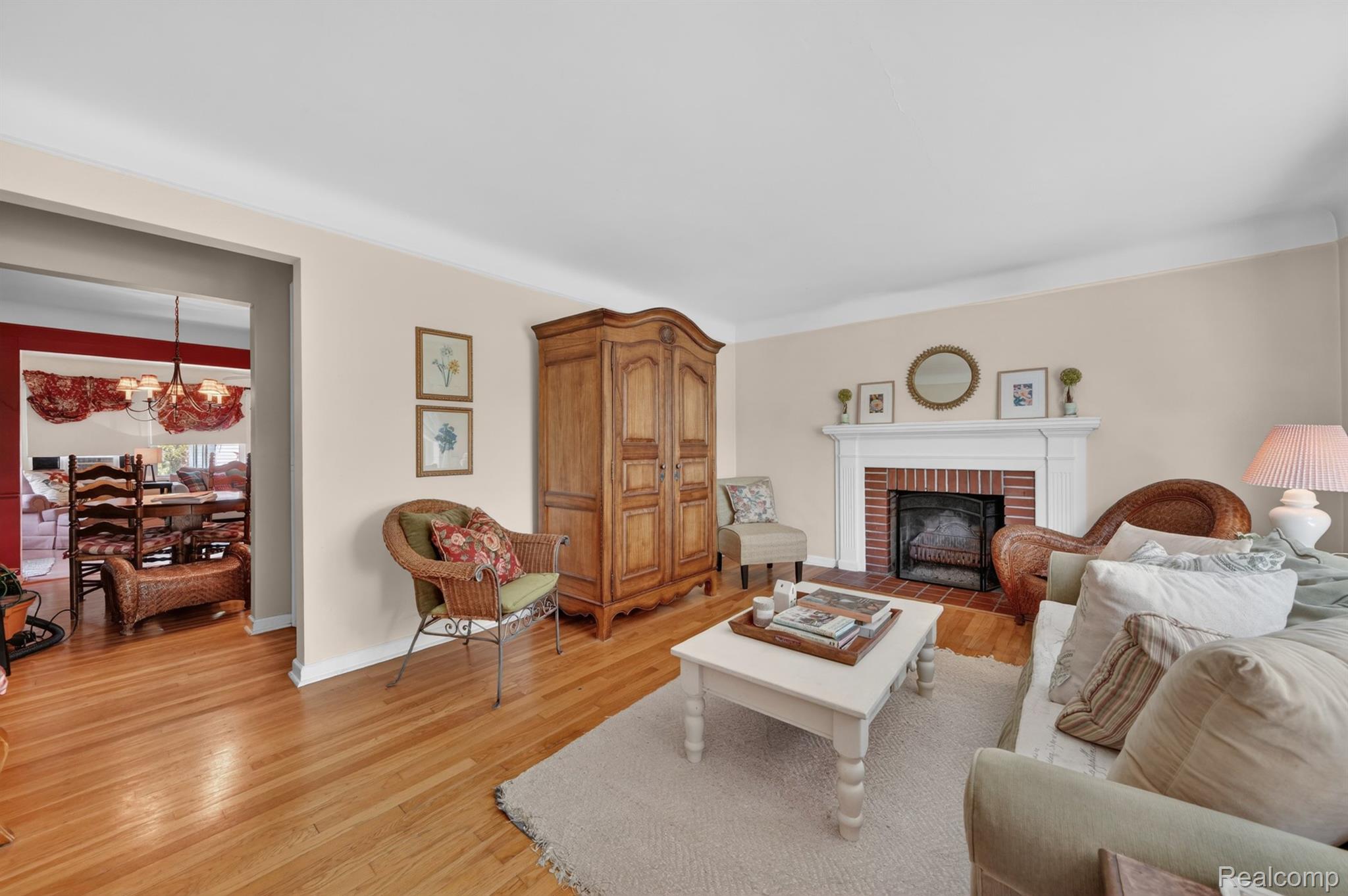 17386 Beverly Road Franklin, MI 48025 - Photo 8 of 28 Living area featuring wood-finish flooring, a white mantel fireplace with brick surround, and crown molding
