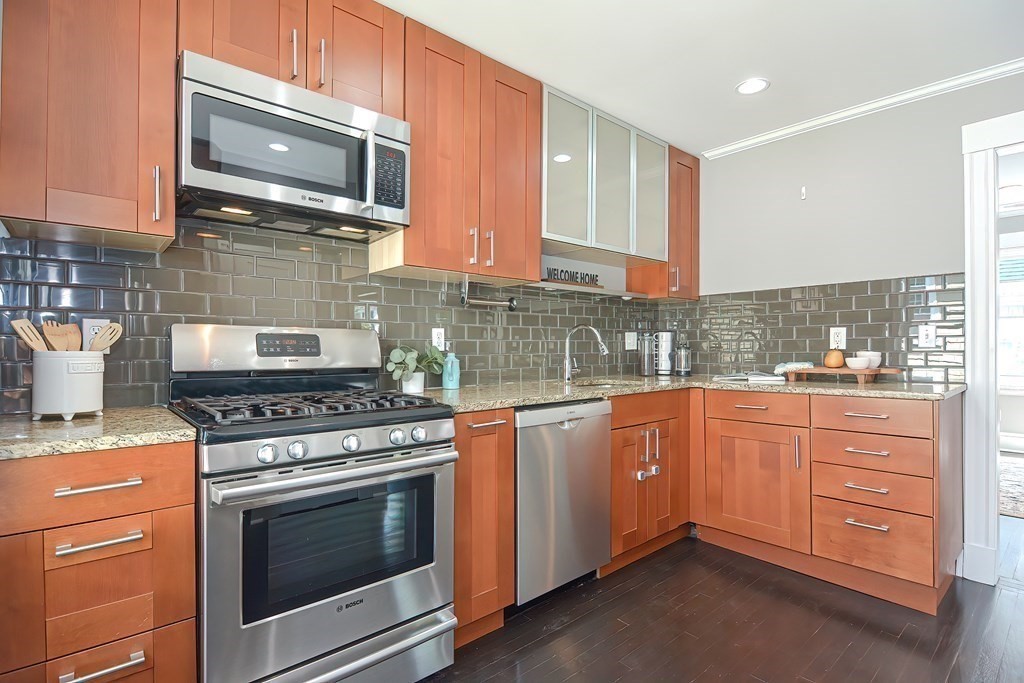 7-9 Goodway Road, Unit 2 Jamaica Plain, MA 02130 - Photo 10 of 39 a kitchen with granite countertop cabinets stainless steel appliances and wooden floor