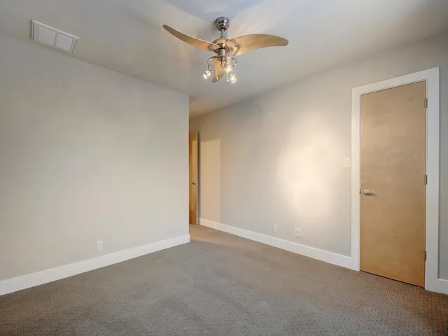 an empty room with a chandelier fan and windows