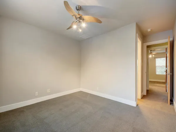 an empty room with an entryway and chandelier fan