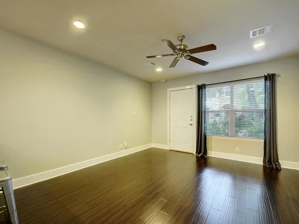 an empty room with wooden floor and windows