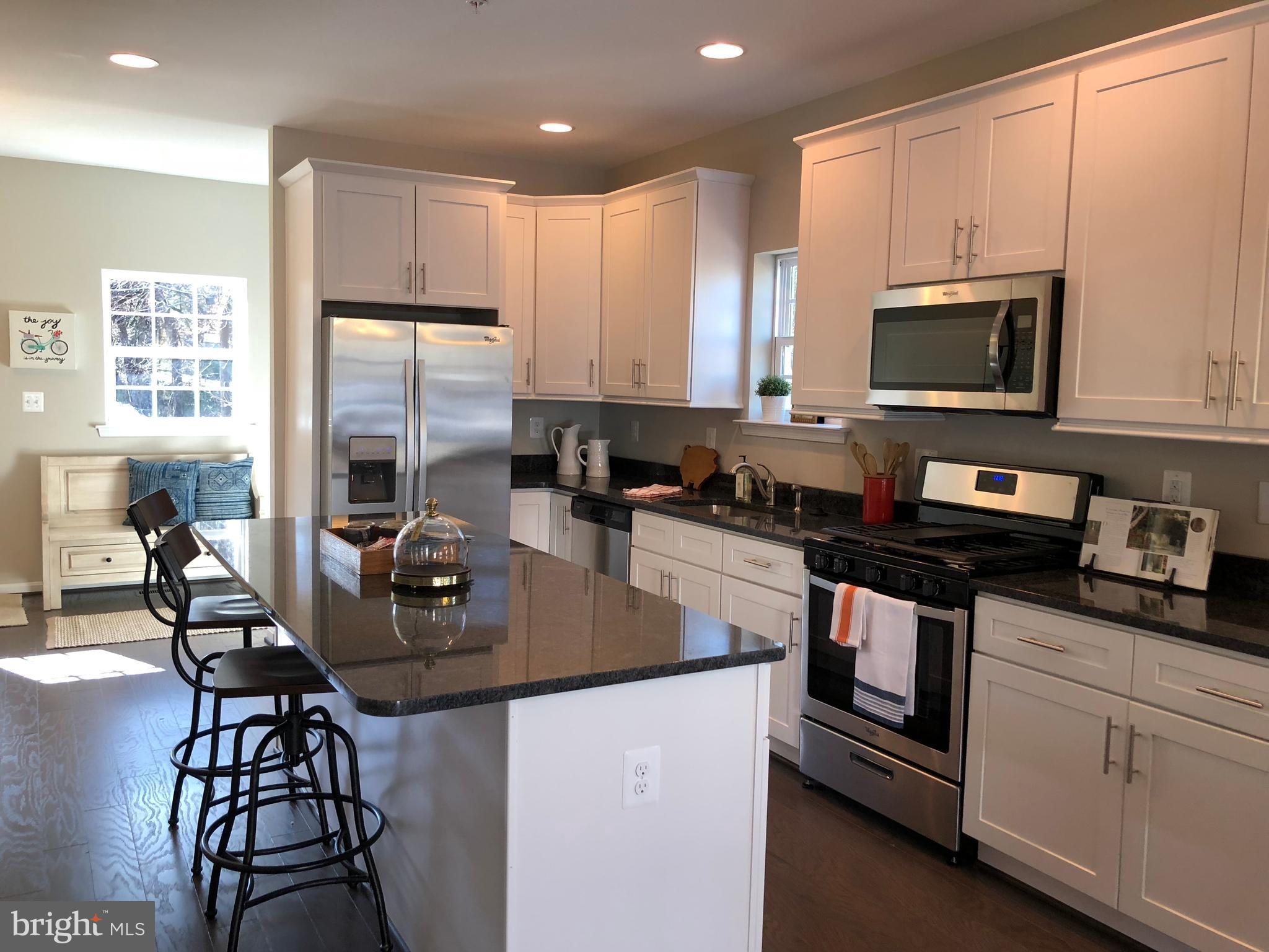 905 Cedarcroft Road Baltimore, MD 21212 - Photo 3 of 28 a kitchen with stainless steel appliances granite countertop a stove a sink a microwave a dining table and chairs with wooden floor