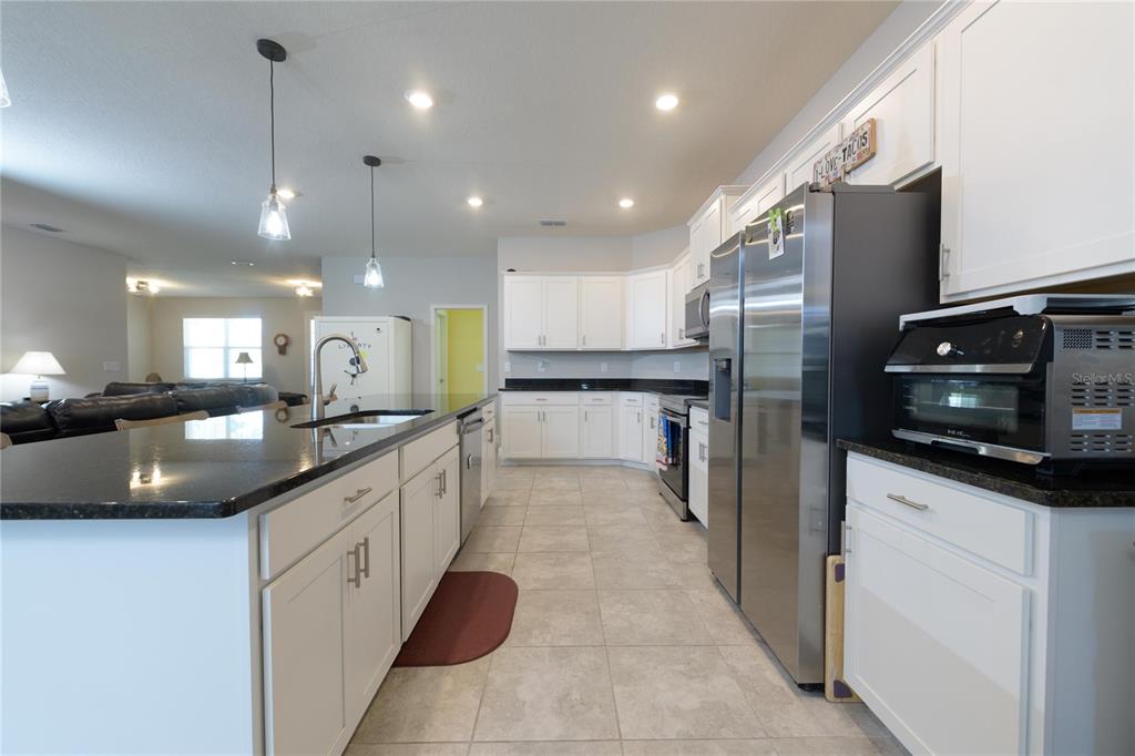 4444 Devinshire Fields Loop Plant City, FL 33567 - Photo 12 of 38 a large kitchen with stainless steel appliances kitchen island a large counter tops a stove a sink and a refrigerator