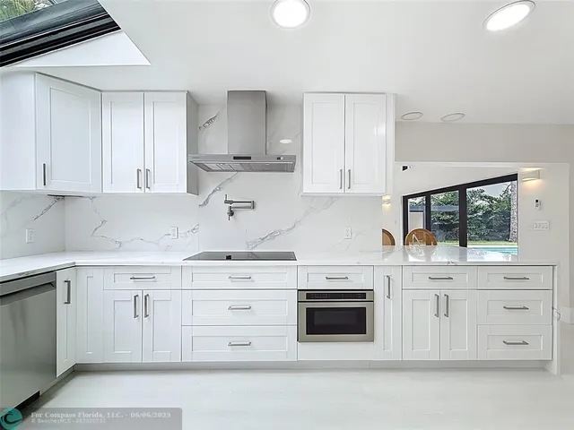 a kitchen with a sink and dishwasher with white cabinets