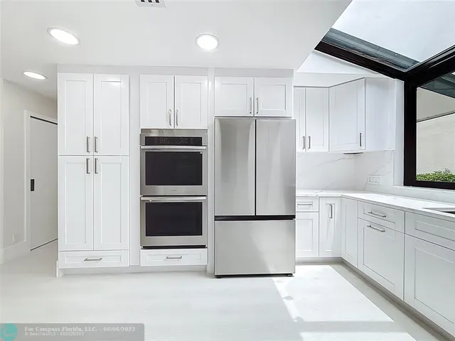 a living room with furniture large windows and a chandelier