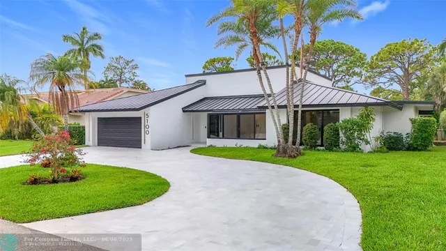 a view of a house with a yard and palm trees