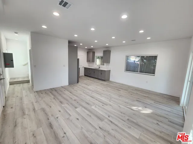 a view of a big room with wooden floor and windows