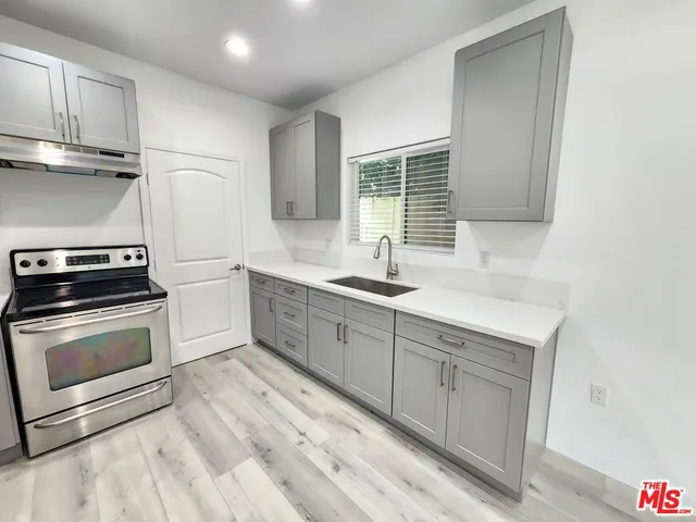 a kitchen with granite countertop a sink stainless steel appliances and cabinets
