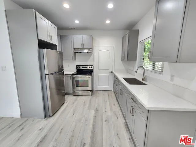 a kitchen with stainless steel appliances granite countertop a refrigerator a sink dishwasher a stove with wooden floors