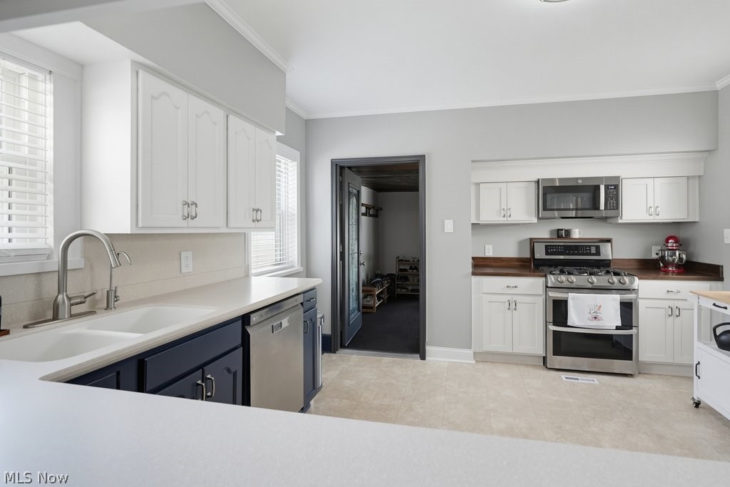 23055 Snell Road Columbia Station, OH 44028 - Photo 11 of 50 Kitchen featuring white upper cabinetry, navy blue lower cabinetry, light-toned countertops, a stainless steel dishwasher, and a stainless steel range with an overhead microwave