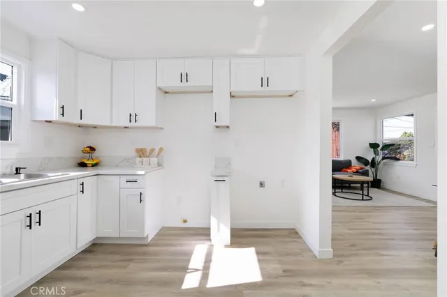 a kitchen with white cabinets and window