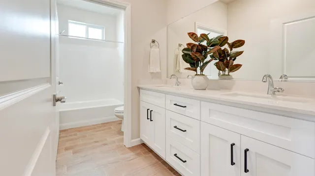 a bathroom with a double vanity sink mirror and bathtub
