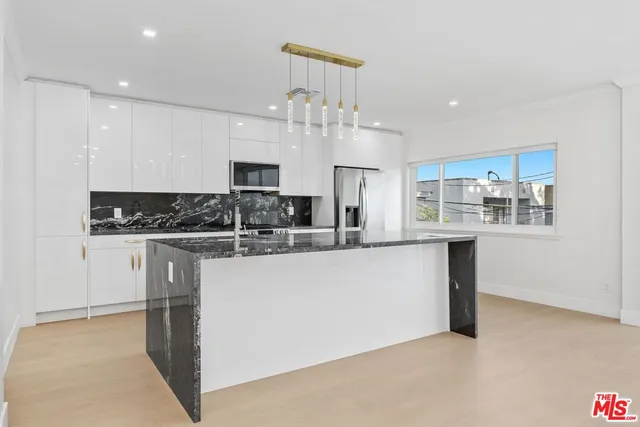 a kitchen with kitchen island granite countertop a sink cabinets and stainless steel appliances