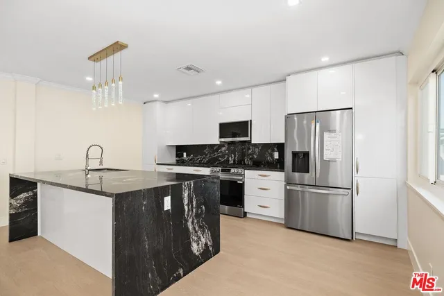 a kitchen with stainless steel appliances granite countertop a refrigerator sink and white cabinets