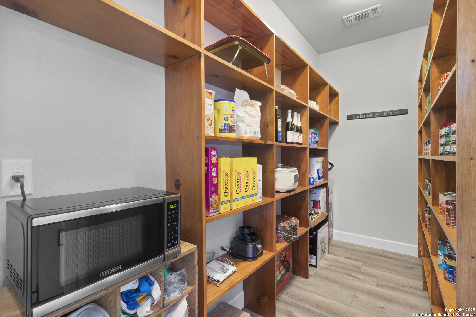 792 Alamo Beach Road Pipe Creek, TX 78063 - Photo 9 of 70 a view of an empty room with wooden floor and a book shelf
