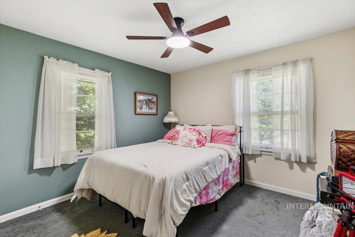 4619 Freemont Street Boise, ID 83706 - Photo 8 of 27 Bedroom featuring a ceiling fan with integrated lighting, a contrasting accent wall, two windows with white trim, and gray carpeted flooring