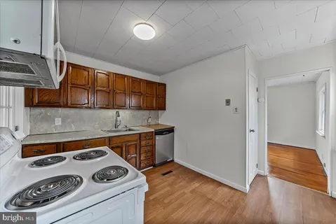 a kitchen with a stove and wooden floor