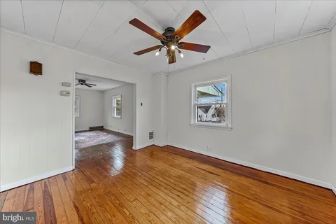 an empty room with wooden floor and ceiling fan