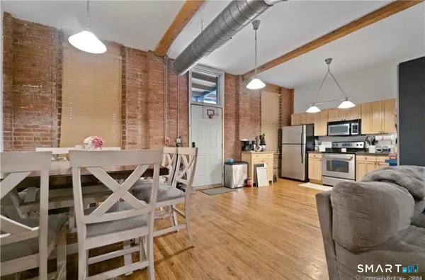 a view of kitchen with stainless steel appliances kitchen island granite countertop dining table chairs sink and cabinets