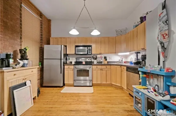 a kitchen with a refrigerator a stove a sink dishwasher and a dining table with wooden floor