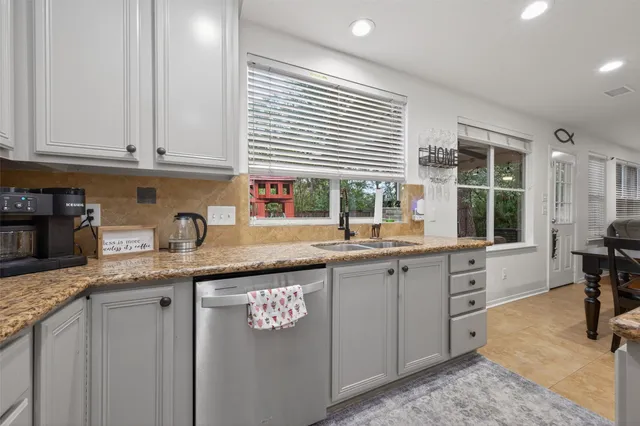 a kitchen with granite countertop a sink a window stainless steel appliances and cabinets