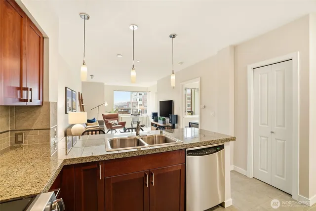 a kitchen with stainless steel appliances granite countertop a sink a stove a dining table and chairs