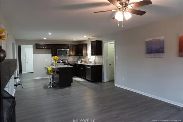 a open kitchen with stainless steel appliances granite countertop a refrigerator a sink dishwasher a stove with wooden cabinets and floor