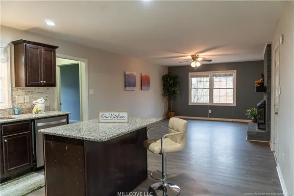a kitchen with kitchen island granite countertop a sink cabinets and wooden floor