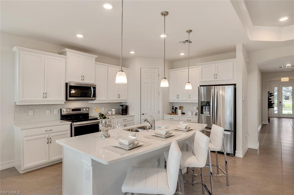 a kitchen with stainless steel appliances kitchen island granite countertop a sink refrigerator and cabinets