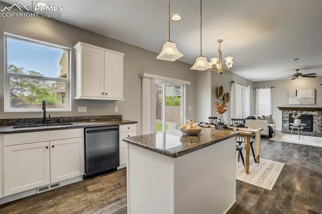 a kitchen with kitchen island granite countertop a sink cabinets and living room view