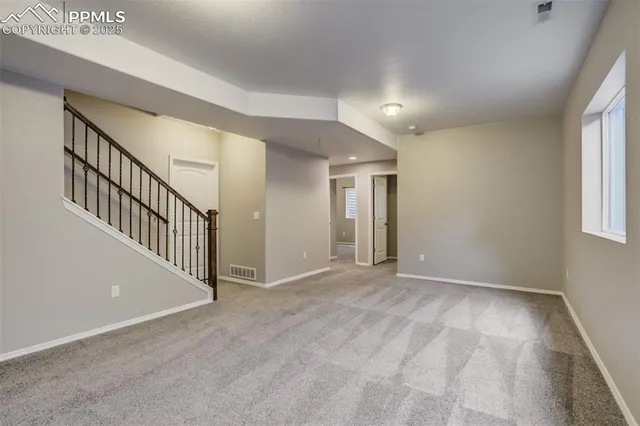 a view of an empty room with wooden floor and windows