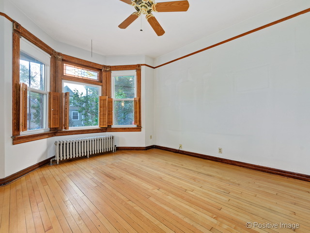 Undisclosed Address Chicago, IL 60613 - Photo 4 of 22 a view of an empty room with a window and wooden floor