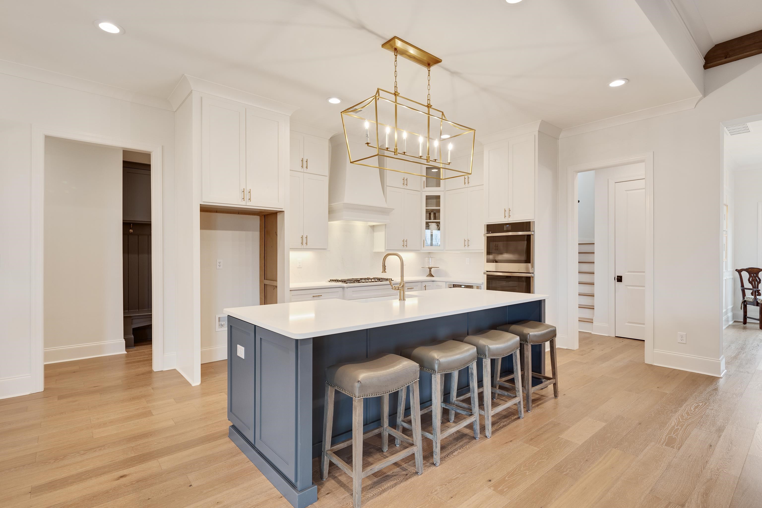 292 Keisie Lane Collierville, TN 38017 - Photo 10 of 40 Kitchen with two tone cabinetry, light wood finished floors, a breakfast bar, ornamental molding, and a kitchen island with sink