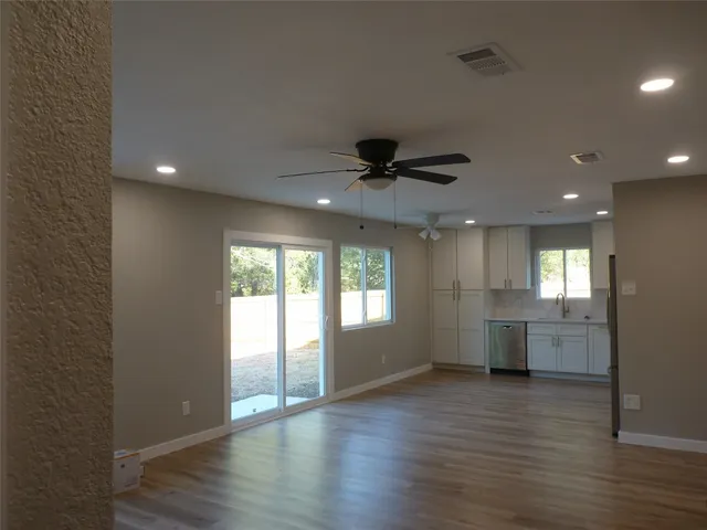 a view of an empty room with window and wooden floor