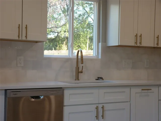 a view of a kitchen sink with cabinets
