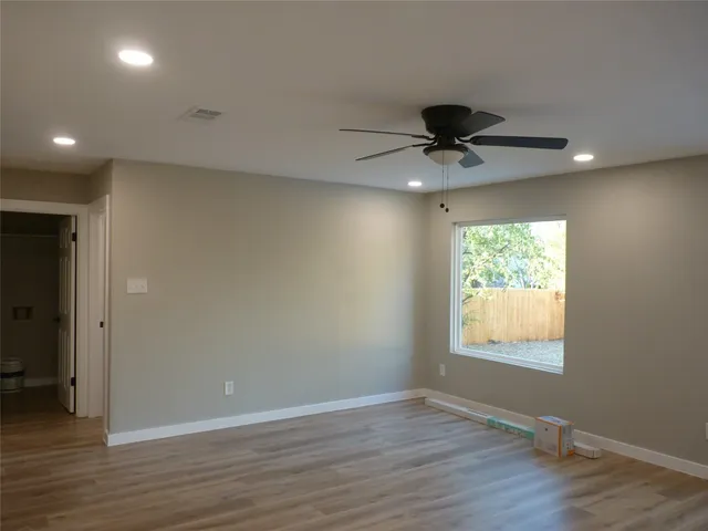 an empty room with wooden floor and chandelier fan