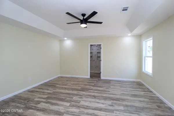 a view of an empty room with window and wooden floor