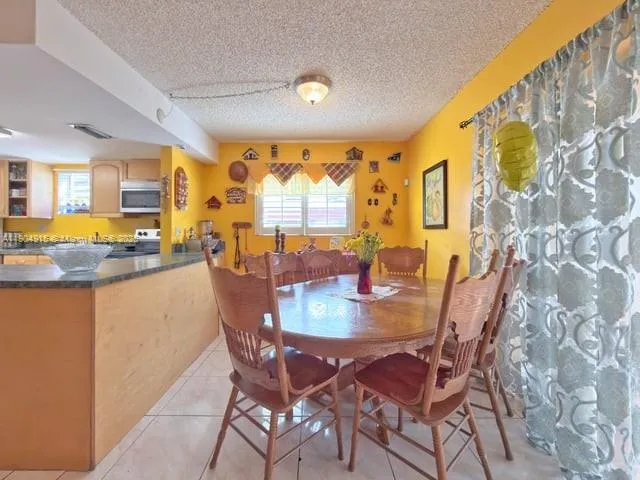 a dining room with stainless steel appliances a dining table and chairs with the floor to ceiling window