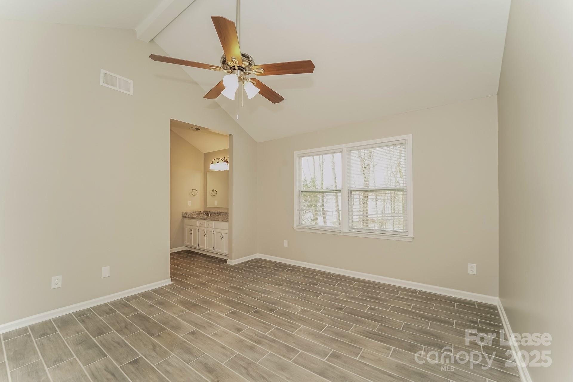 8301 Rocester Drive Charlotte, NC 28215 - Photo 8 of 16 an empty room with wooden floor fan and windows